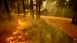 Flames from the Caldor Fire scorch the ground near a structure in Grizzly Flats, Calif., Wednesday, Aug. 18, 2021. 
