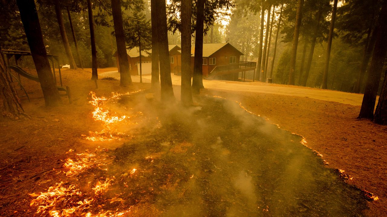 Flames from the Caldor Fire scorch the ground near a structure in Grizzly Flats, California, Wednesday, Aug. 18, 2021.