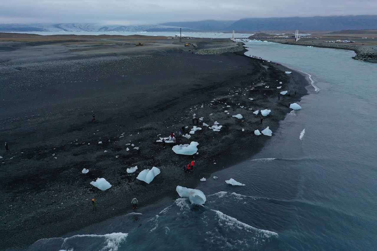 People in Hof, Iceland, walk among chunks of ice Sunday, August 15, that originated from the Breidamerkurjokull glacier seen in the background. The glacier is melting because of global warming, annually losing 100-300 meters in length. 