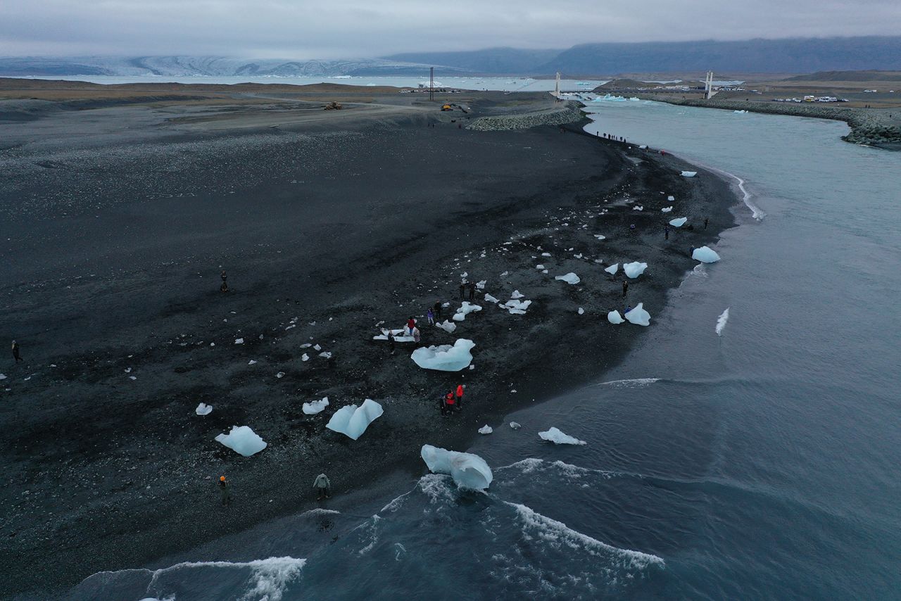 People in Hof, Iceland, walk among chunks of ice Sunday, August 15, that originated from the Breidamerkurjokull glacier seen in the background. The glacier is melting because of global warming, annually losing 100-300 meters in length.
