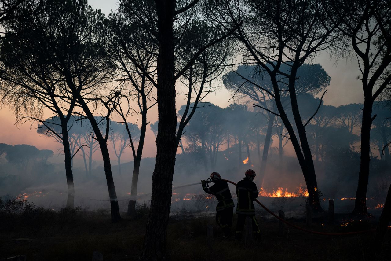 Firefighters use a hose to extinguish a wildfire near Le Luc, France, on Tuesday, August 17. Thousands of people fled homes, campgrounds and hotels near the French Riviera as firefighters battled a blaze that raced through nearby forests and sent smoke pouring down wooded slopes toward vineyards.