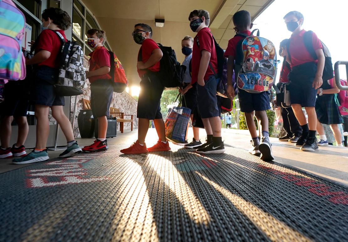 Wearing masks to prevent the spread of Covid-19, elementary school students line up to enter school for the first day of classes in Richardson, Texas, on August 17, 2021.