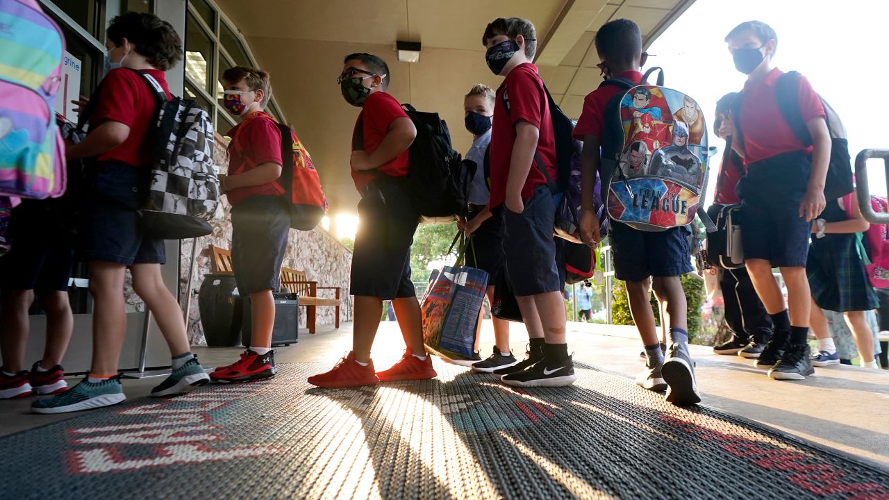Wearing masks to prevent the spread of Covid-19, elementary school students line up to enter school for the first day of classes in Richardson, Texas, on August 17, 2021. 