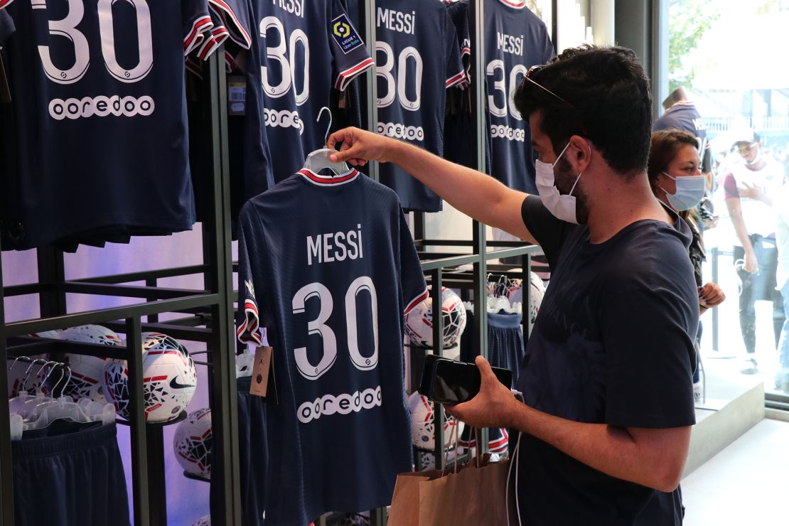 Soccer fans inspect Lionel Messi's PSG no 30 shirts during Messi's press conference announcing his signing with the club in Paris on August 11, 2021. Messi, the six time Ballon d'Or trophy winner with FC Barcelona, signed a 2-year contract with an option for a third year with the French club. 