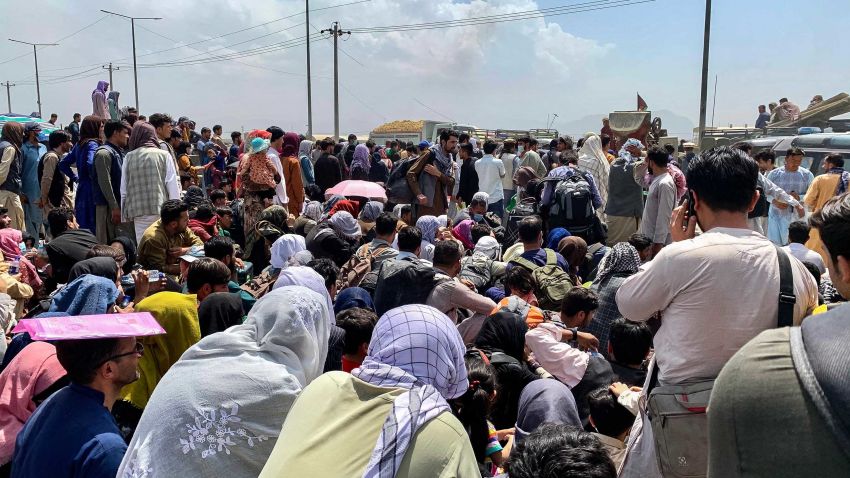 Afghan people gather along a road as they wait to board a U S military aircraft to leave the country, at a military airport in Kabul on August 20, 2021 days after Taliban's military takeover of Afghanistan. (Photo by Wakil KOHSAR / AFP) (Photo by WAKIL KOHSAR/AFP via Getty Images)