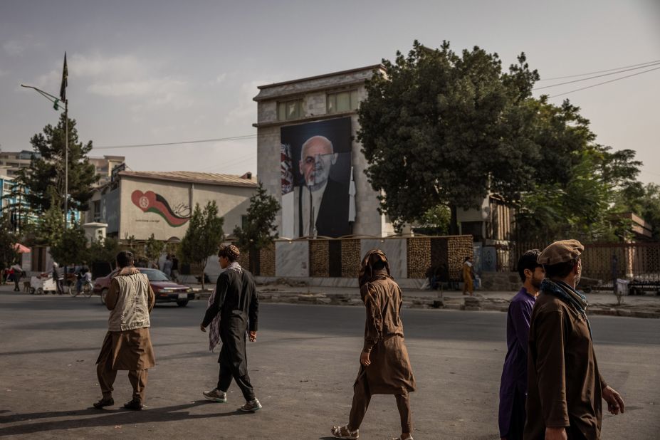 People walk past a half-destroyed poster of former Afghan President Ashraf Ghani in Kabul on August 18.