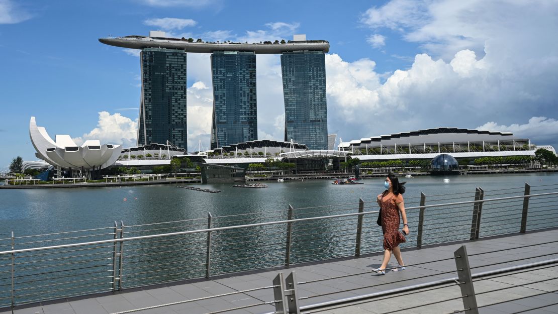 A woman takes a walk across the water from Singapore's Marina Bay Sands hotel and resort in August 2021.
