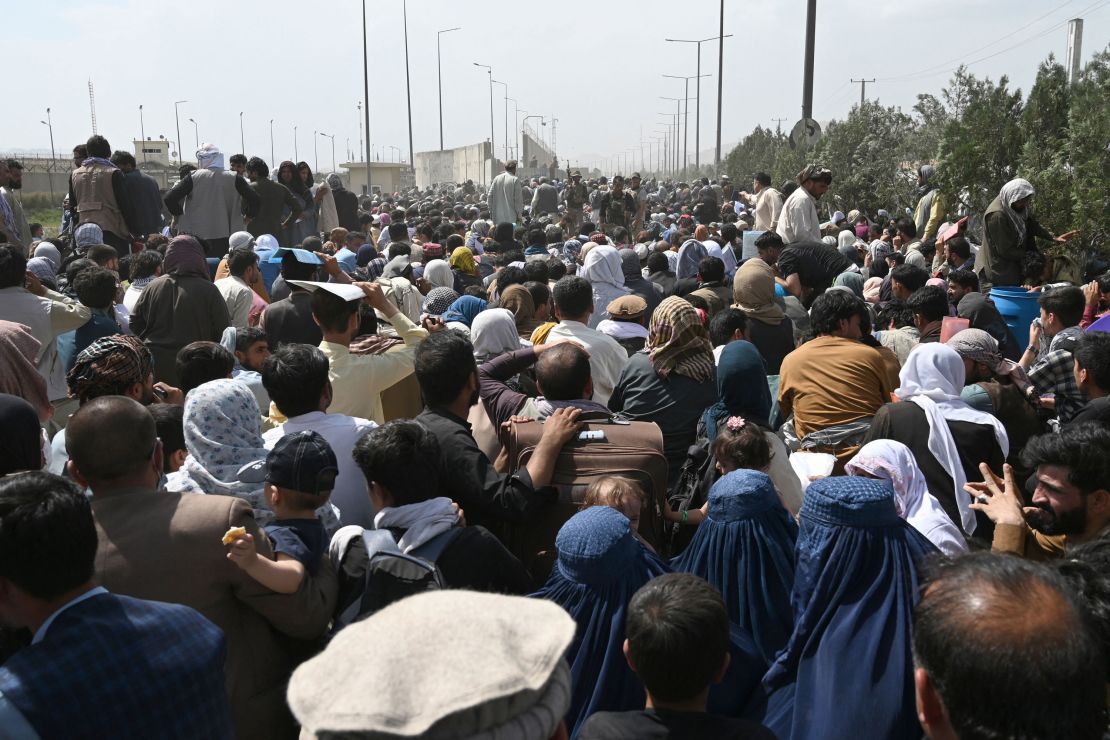 Afghans gather on a roadside near the military part of the airport in Kabul on August 20, 2021, hoping to flee from the country after the Taliban's military takeover of Afghanistan.
