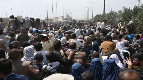 Afghans gather on a roadside near the military part of the airport in Kabul on August 20, 2021.
