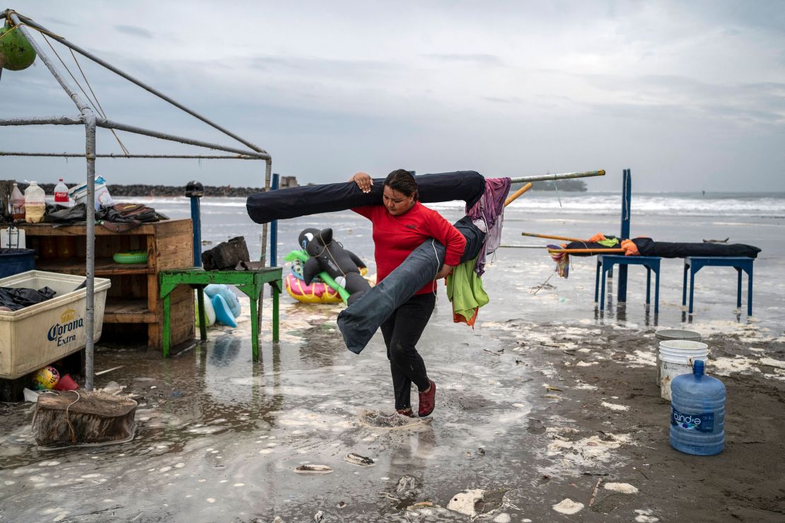 A woman removes umbrellas from the beach as strong waves reach the coast due to Hurricane Grace in Boca del Rio, Veracruz, Mexico, on August 20, 2021. 