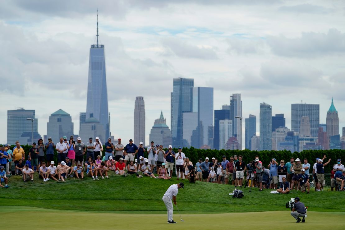 Jon Rahm, of Spain, putts on the 18th green as the Manhattan skyline looms in the distance.
