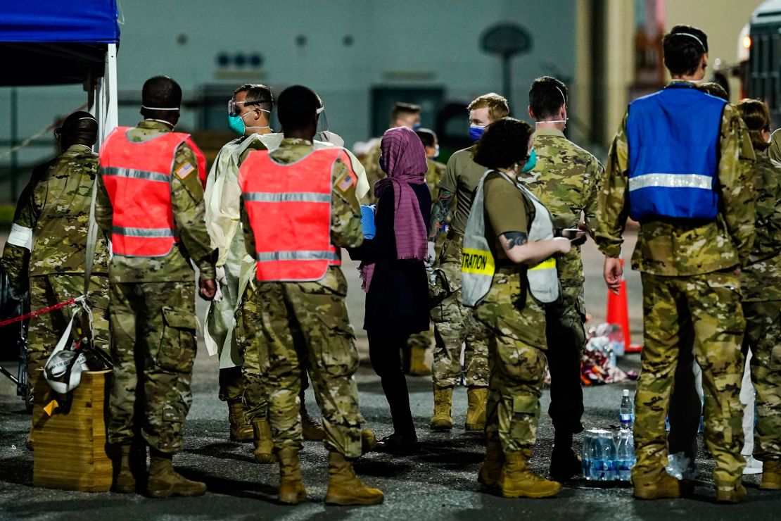 People flown out of Afghanistan leave a transport bus at Ramstein Air Base and are met by soldiers and helpers.