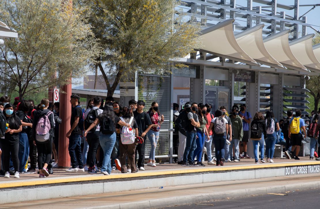 Students wait for the Valley Metro bus to pick them up after their first day at Central High School in Phoenix on August 2, 2021.