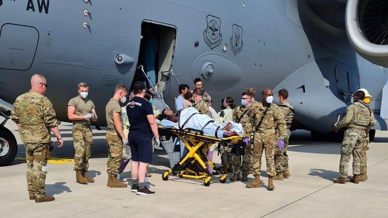 Medical support personnel help an Afghan mother, whose identity has been digitally obscured at source, with her family off a US Air Force C-17 transport aircraft moments after she delivered a child aboard the aircraft upon landing at Ramstein Air Base, Germany, on Saturday.