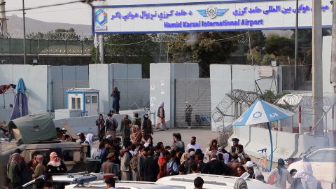 Taliban fighters stand guard as Afghans gather outside the Hamid Karzai International Airport to flee the country, in Kabul, Afghanistan, on Saturday, August 21.