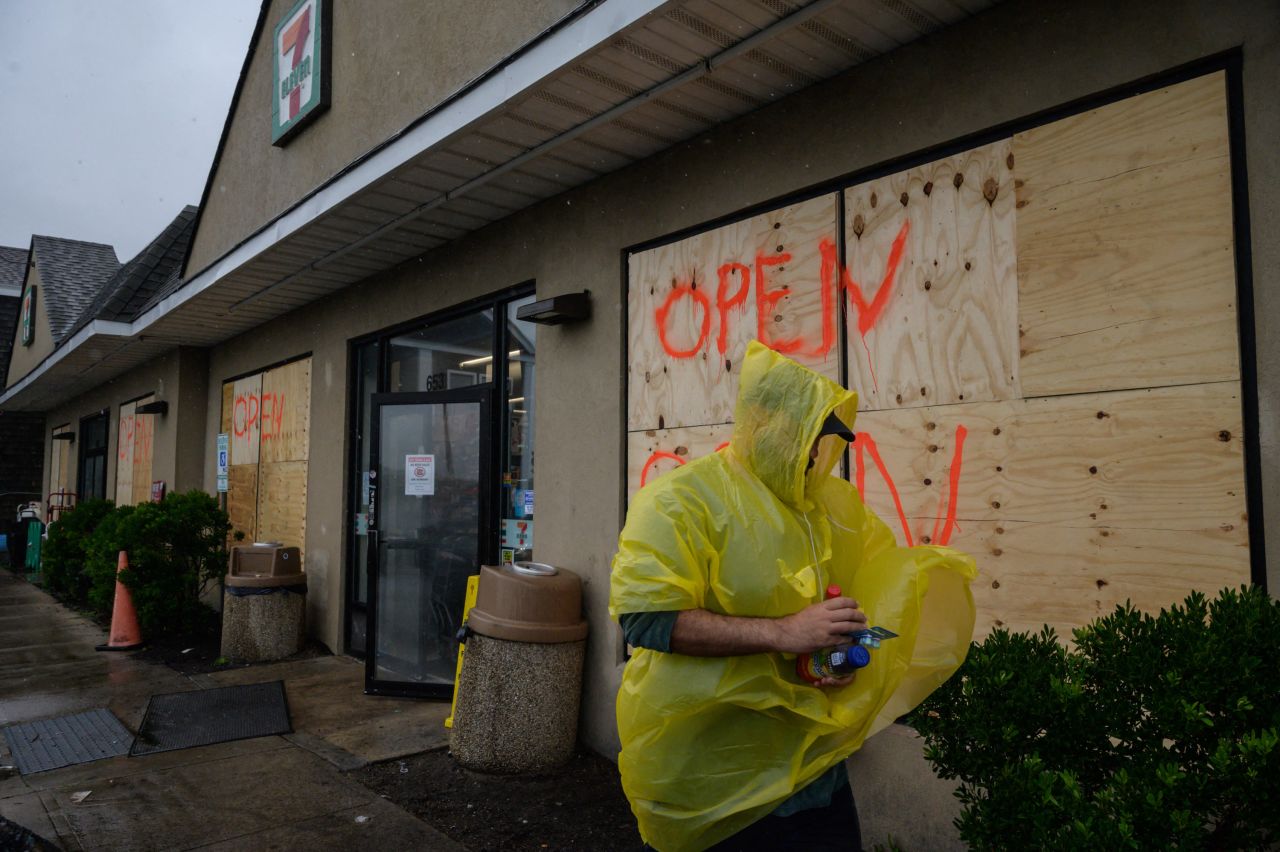 A man walks outside a boarded-up convenience store in Montauk, New York, on August 22.