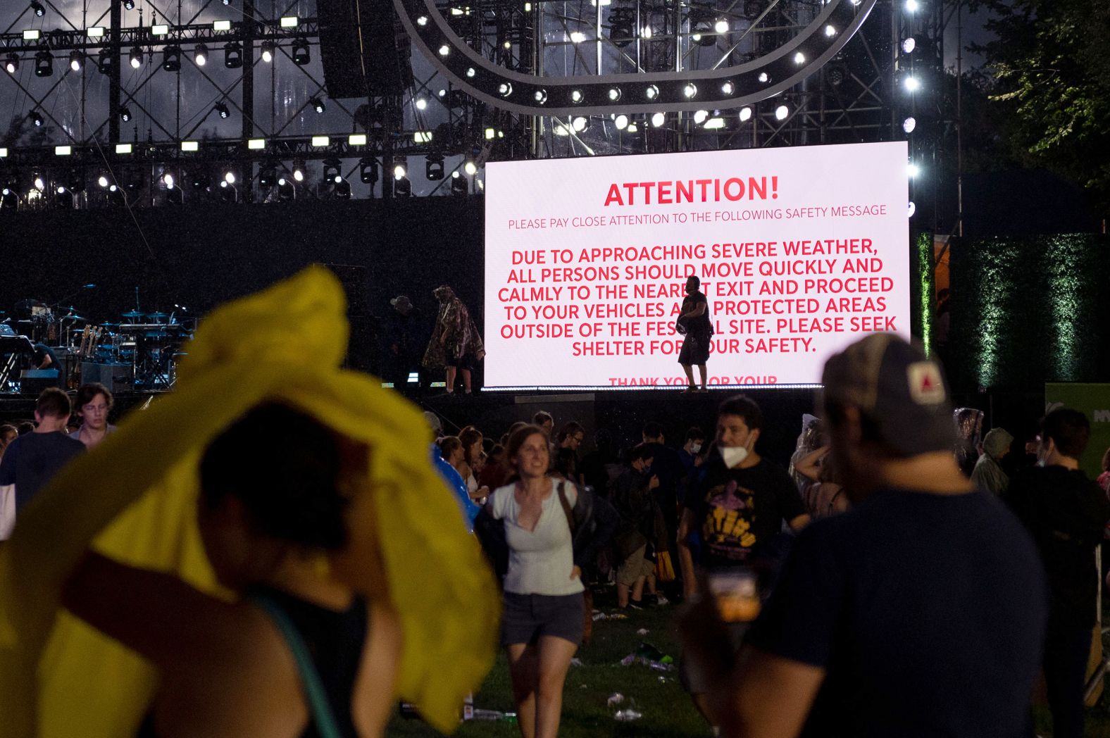 A severe weather warning is displayed on a screen, asking audience members to seek shelter.