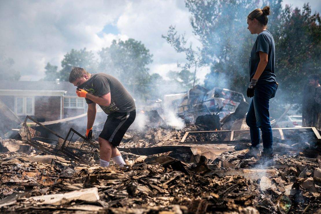 Josh Whitlock and Stacy Mathieson look through what is left of their home after it burned following flooding in Waverly, Tennessee.