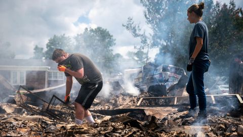 Josh Whitlock and Stacy Mathieson look through what is left of their home after it burned following flooding in Waverly, Tennessee.