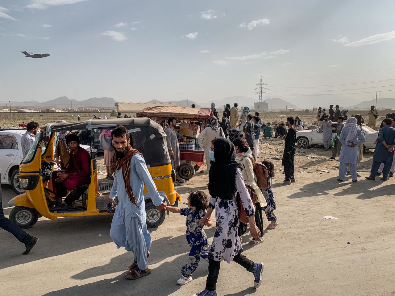 People gather outside the airport in Kabul as a military transport plane takes off on August 21.