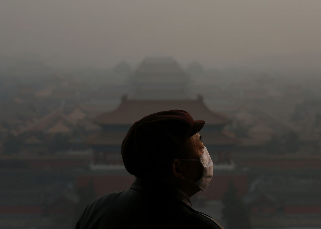 A tourist wearing a face mask looking at the Forbidden City through heavy smog in Beijing, China, on January 16, 2013.