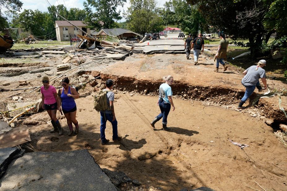 People walk across a washed-out road in Waverly, Tennessee, on Sunday, August 22.