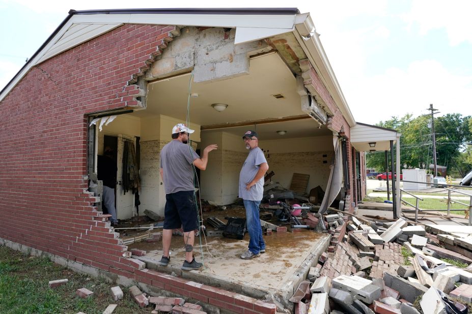 Brian Mitchell, right, is joined by friend Chris Hoover while looking through his mother-in-law's damaged Waverly home on August 22.
