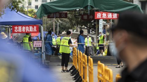 Police, security guards and volunteers stand at an entrance of a neighborhood placed under lockdown in Shanghai, China on August 21, after a resident tested positive for Covid-19.