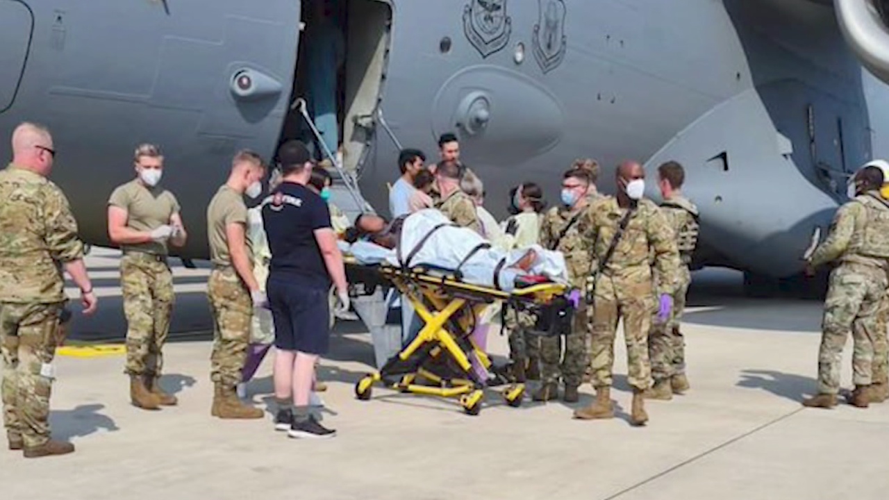 Medical support personnel help an Afghan mother, whose identity has been digitally obscured at source, with her family off a US Air Force C-17 transport aircraft moments after she delivered a child aboard the aircraft upon landing at Ramstein Air Base, Germany, on Saturday.