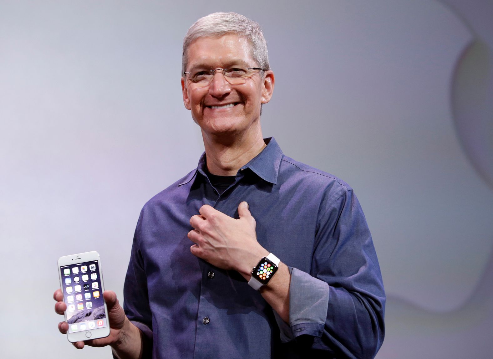 Cook, holding an iPhone 6 Plus and wearing an Apple Watch, discusses the new products during an event in Cupertino in September 2014.