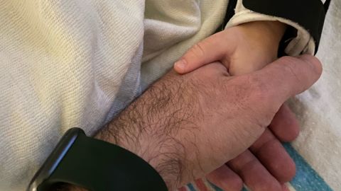 Ben Tinker holds his 16-month-old son's hand while he sleeps in the pediatric intensive care unit.
