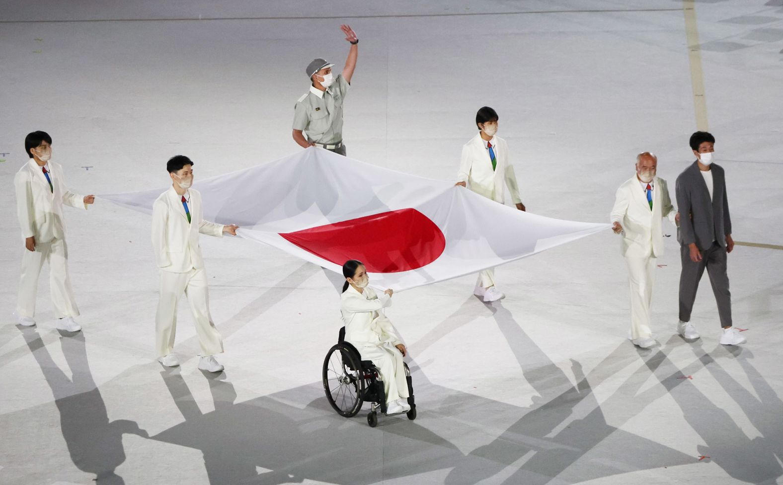Health-care workers present the Japanese flag during the opening ceremony. The Paralympics are taking place amid Japan's worst outbreak of Covid-19.