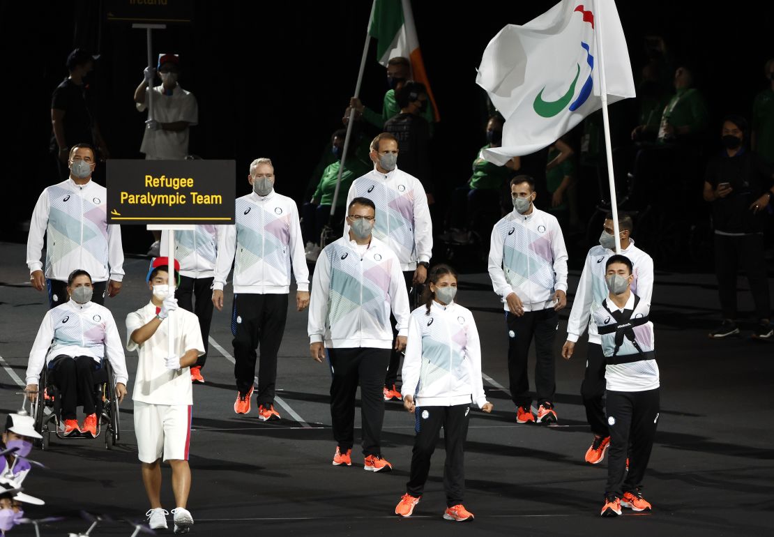 Karimi (right) led the Refugee Paralympic Team with fellow flagbearer Alia Issa (center left) in the parade of athletes during the Opening Ceremony of the Tokyo 2020 Paralympic Games.