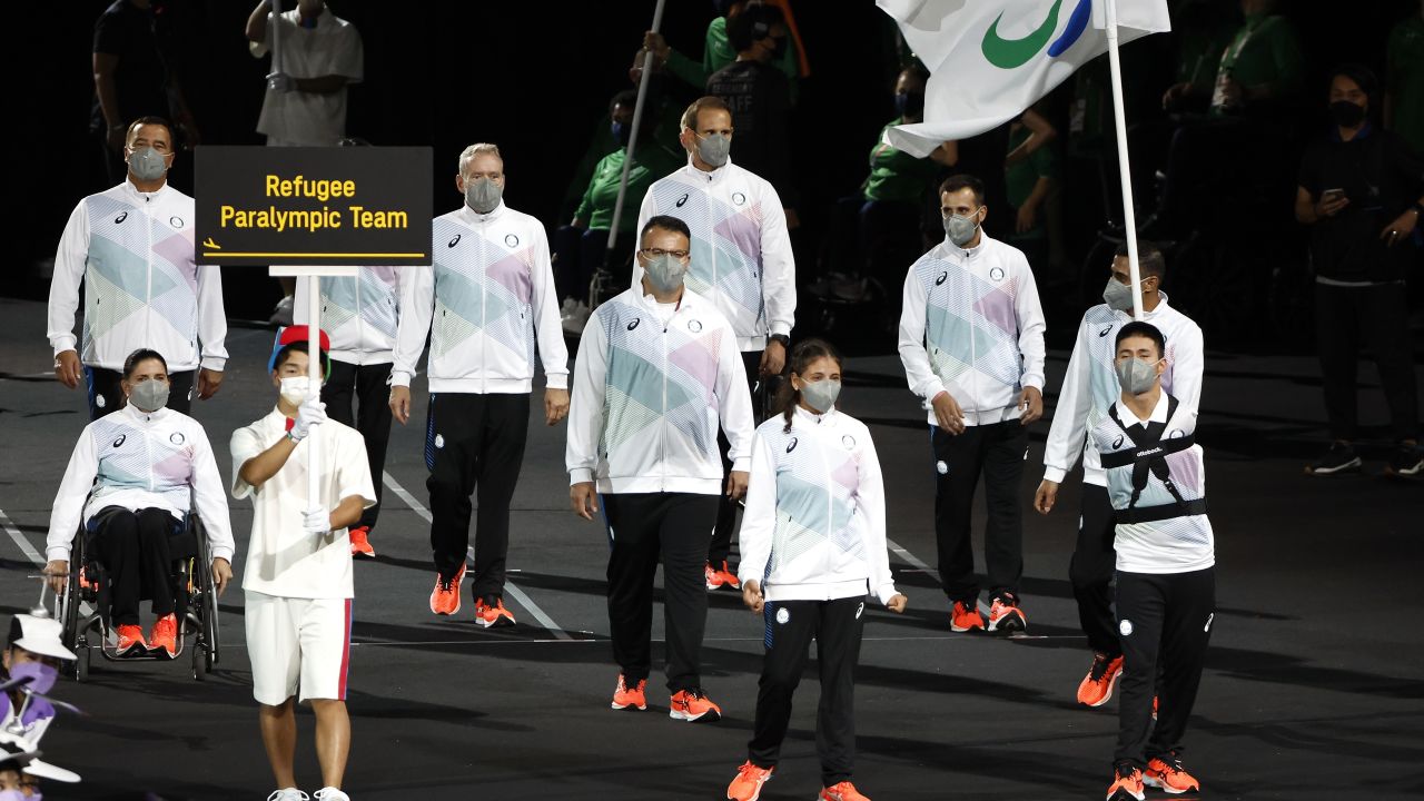 Karimi (right) led the Refugee Paralympic Team with fellow flagbearer Alia Issa (center left) in the parade of athletes during the Opening Ceremony of the Tokyo 2020 Paralympic Games.