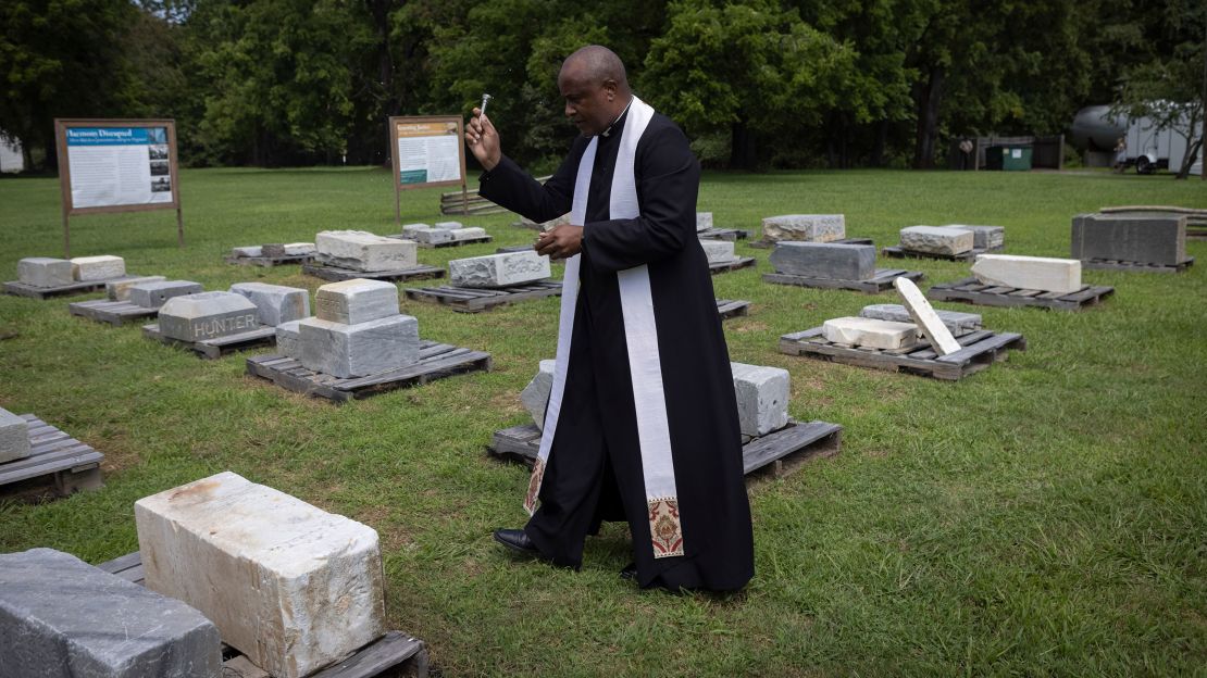 Rev. Lee Gandiya of St. Paul's Episcopal Church blesses gravestones during a ceremonial transfer Monday.