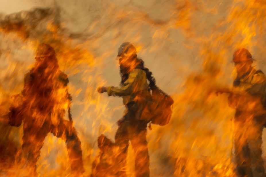 Firefighters are seen behind the flames of a backfire they were setting to battle the French Fire near Wofford Heights.