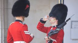 A member of The Coldstream Guards, on duty at Buckingham Palace, is given a drink of water during the extreme heat of the afternoon, on June 25, 2020. 