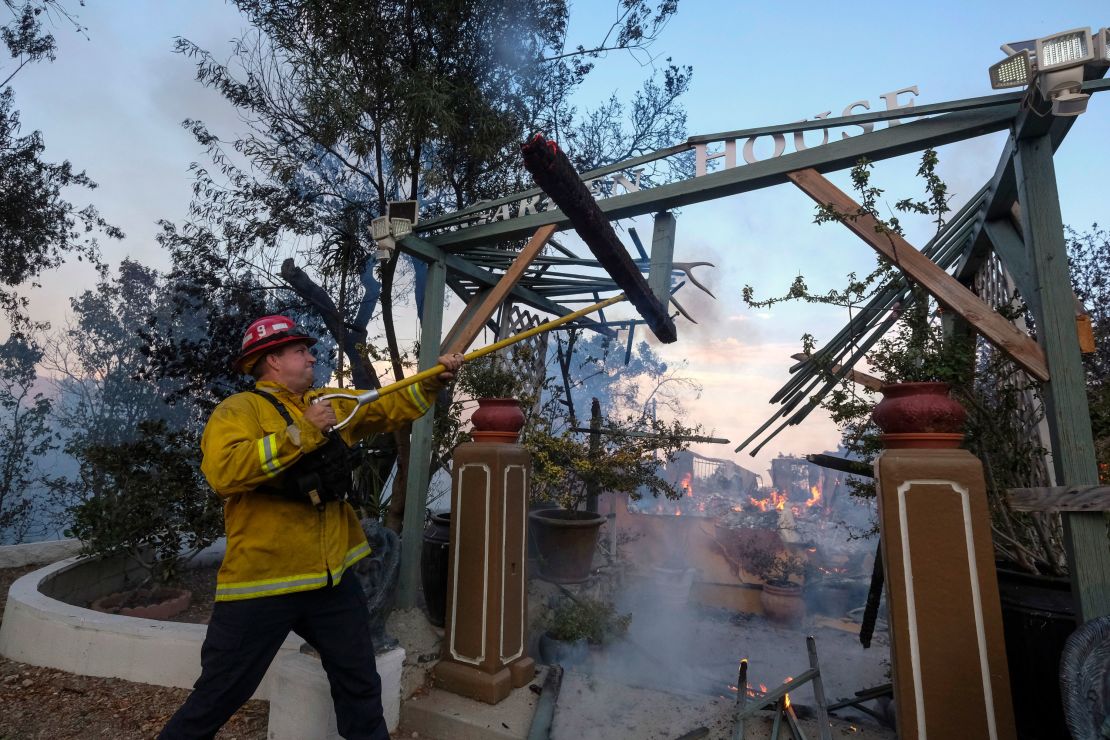 A firefighter works on a burning house as the South Fire burns in Lytle Creek, San Bernardino County, California.