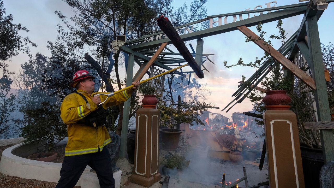 A firefighter works on a burning house as the South Fire burns in Lytle Creek, San Bernardino County, California.