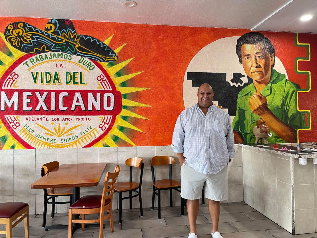 Alejandro Chavez poses in front of a mural of his granddad at a Tucson, Arizona, taqueria. 