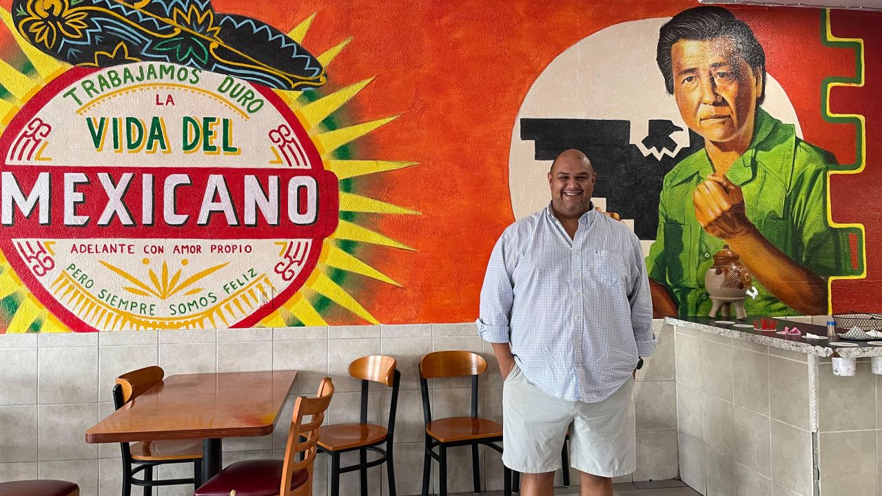 Alejandro Chavez poses in front of a mural of his granddad at a Tucson, Arizona, taqueria. 