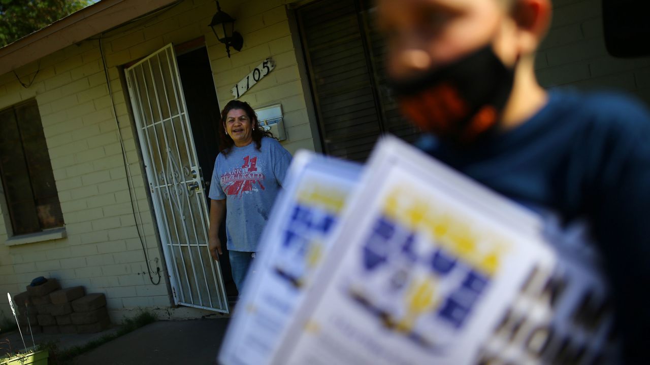 A resident watches people distribute posters during a political event in Phoenix on October 31. 