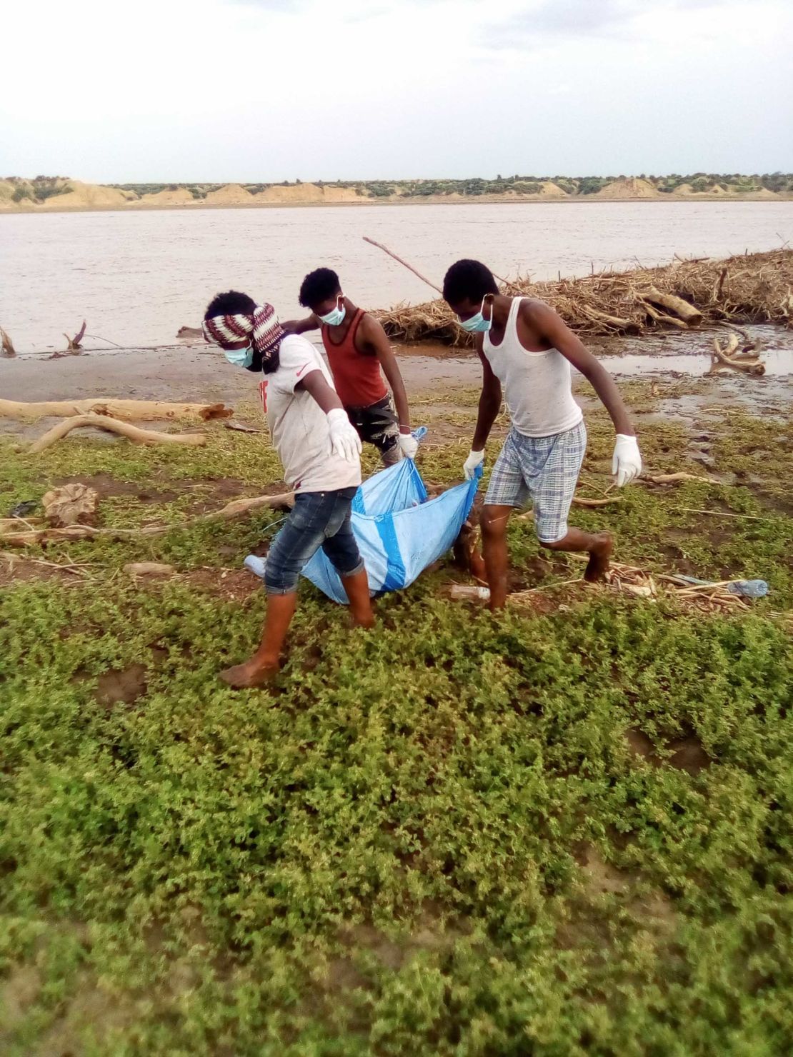 A body recovered from the Setit River bank by Wad El Hilou, Sudan, is carried on plastic sheeting.