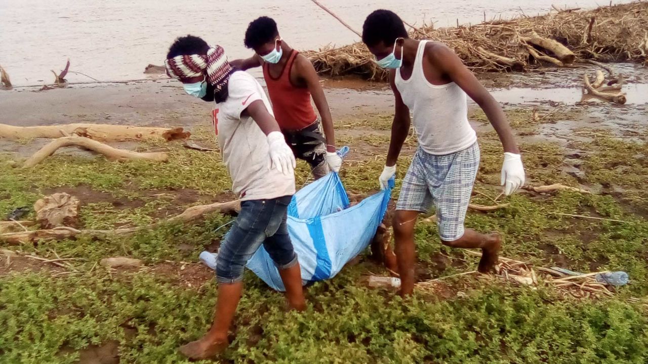 A body recovered from the Setit River bank by Wad El Hilou, Sudan, is carried on plastic sheeting.
