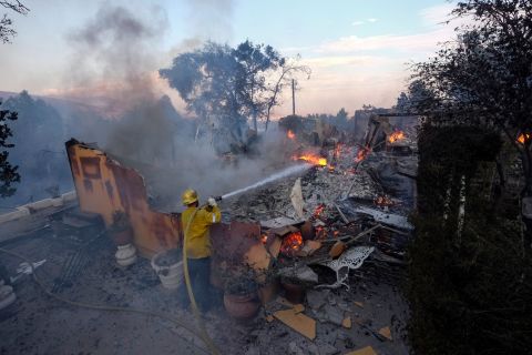 A firefighter tries to extinguish flames at a burning house as the South Fire burned in Lytle Creek, California, on August 25.