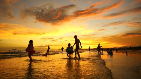 People play by the beach at Sanya Bay against the sunset in Sanya city, south China's Hainan province 22 July 2020.No Use China. No Use France.
