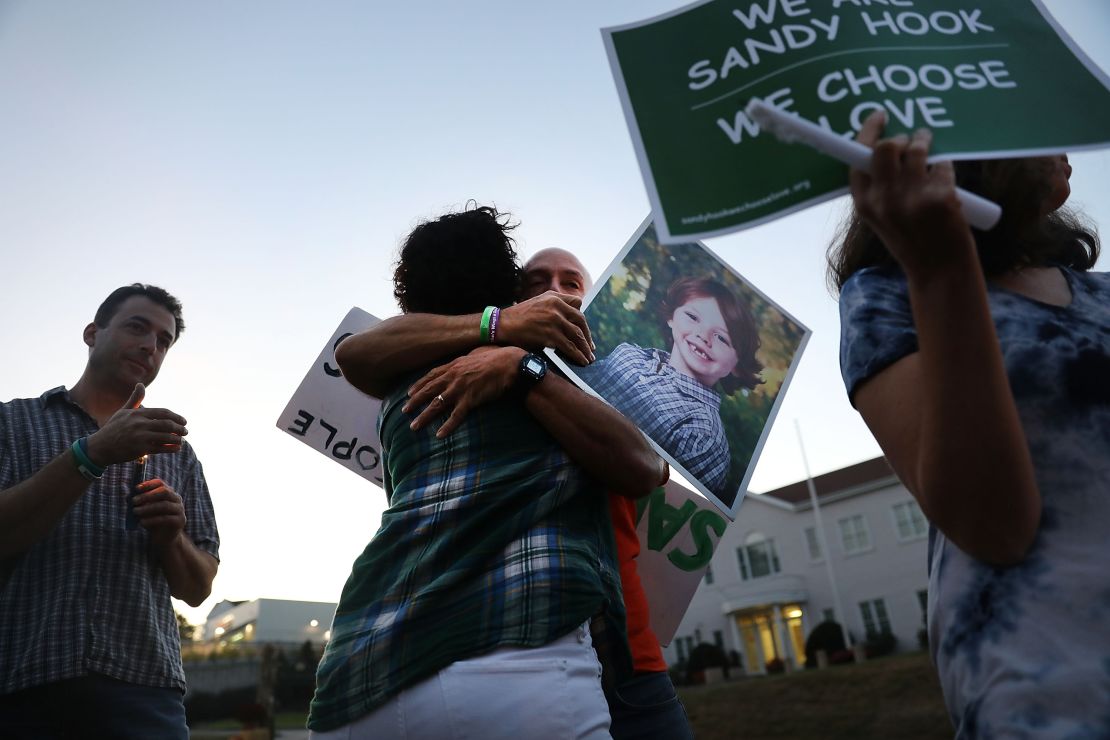 Mark Barden gets a hug while holding up a picture of his son Daniel, who was killed inside Sandy Hook Elementary Schools on December 14, 2012.
