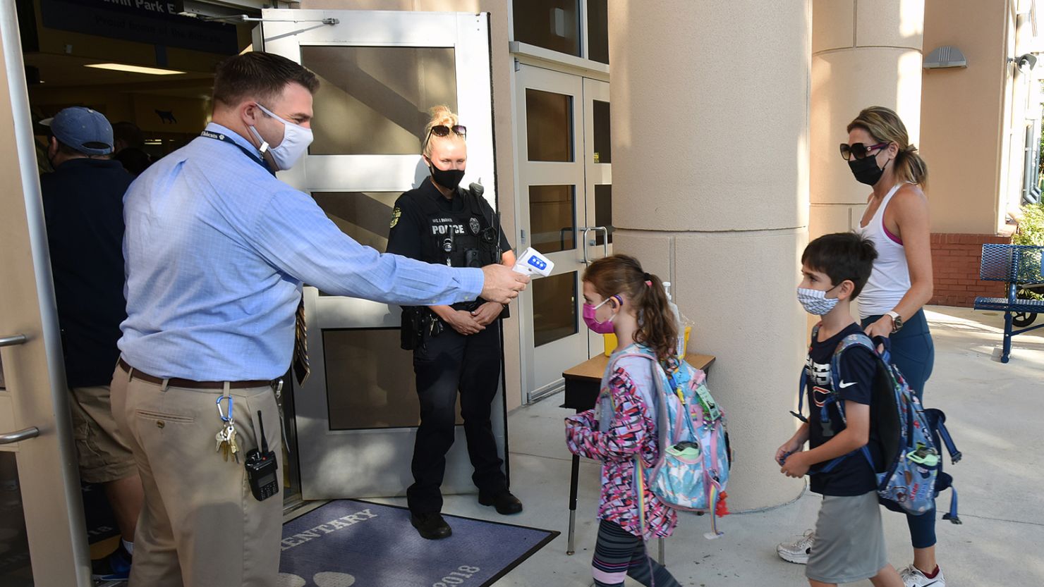 Principal Nathan Hay checks students' temperatures as they arrive on the first day of classes for the 2021-22 school year at Baldwin Park Elementary School in Orlando, Florida, on August 10, 2021.