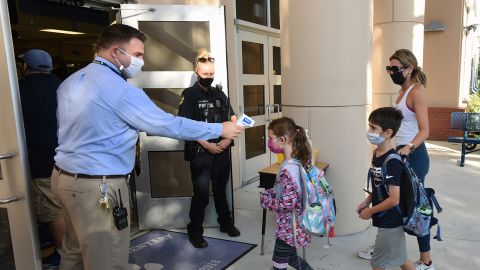 Principal Nathan Hay checks students' temperatures as they arrive on the first day of classes for the 2021-22 school year at Baldwin Park Elementary School in Orlando, Florida, on August 10, 2021.