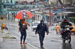 People walk under the rain in Havana on August 27, 2021, as Hurricane Ida passes through eastern Cuba.